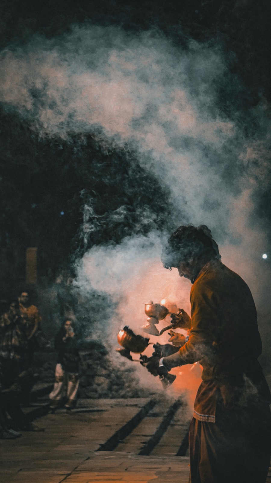 Aarti priest with smoke and fire pots at dusk